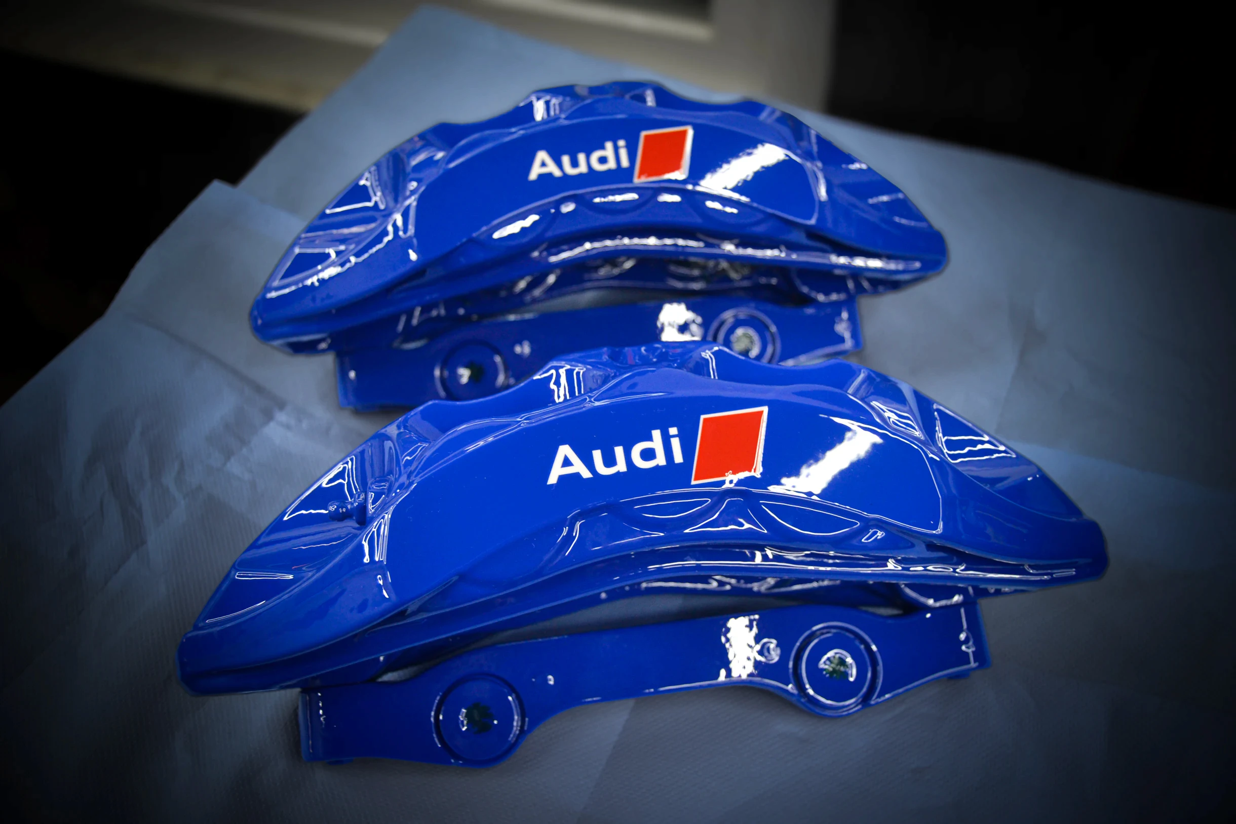 Zwei glänzend blaue Bremssättel mit Audi-Schriftzug bei AT Plus.